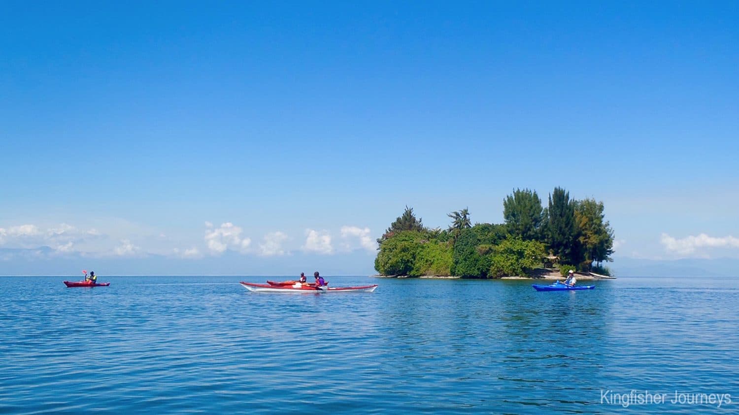 Kayakers paddling past an island on Lake Kivu